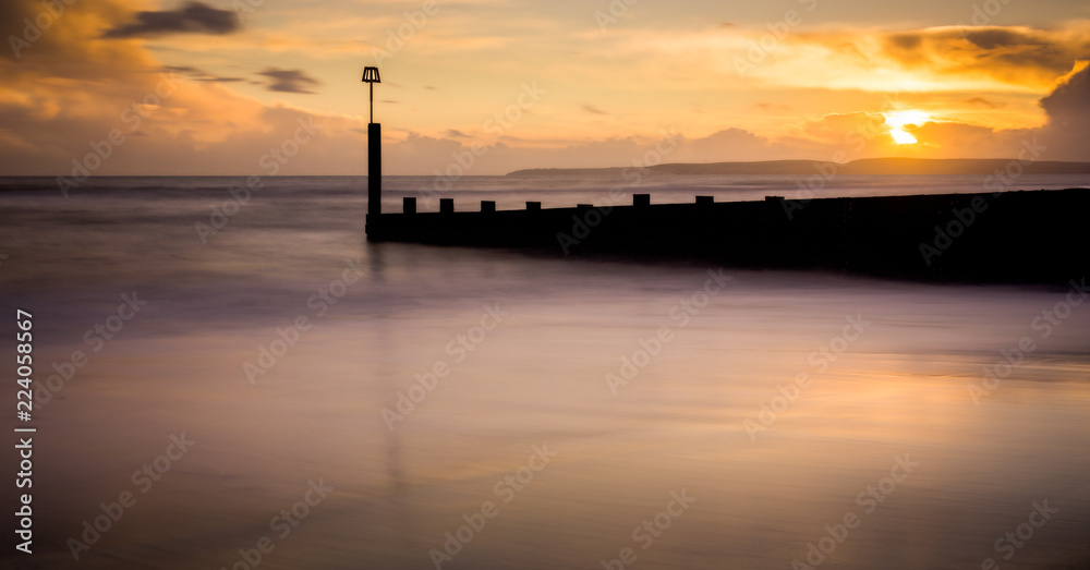 Sunset long exposure shot of sea front groyne with very smooth sea