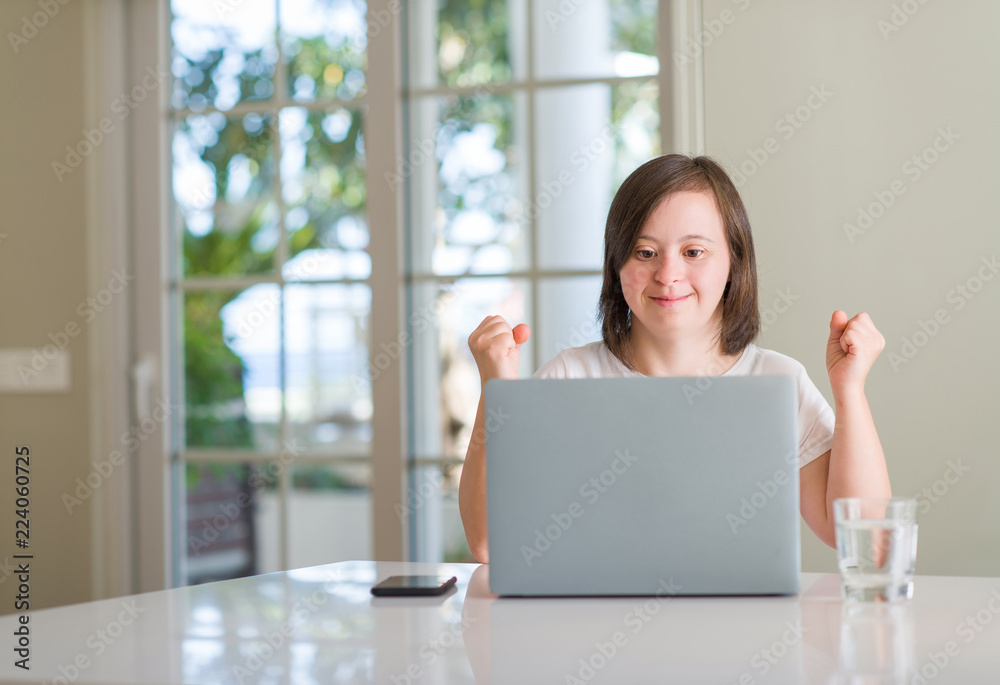 Down syndrome woman at home using computer laptop screaming proud and celebrating victory and success very excited, cheering emotion Down syndrome woman at home using computer laptop screaming proud and celebrating victory and success very excited, cheering emotion