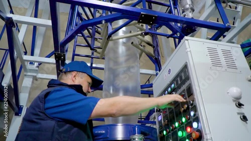 Worker checking and set up LDPE Plastic Blown film bag making machine inside cleanroom for industrial export.