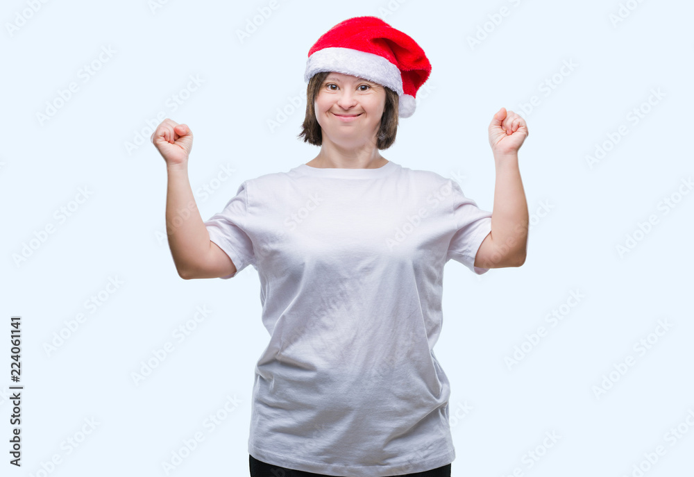Young adult woman with down syndrome wearing christmas hat over isolated background celebrating mad and crazy for success with arms raised and closed eyes screaming excited. Winner concept Young adult woman with down syndrome wearing christmas hat over isolated background celebrating mad and crazy for success with arms raised and closed eyes screaming excited. Winner concept