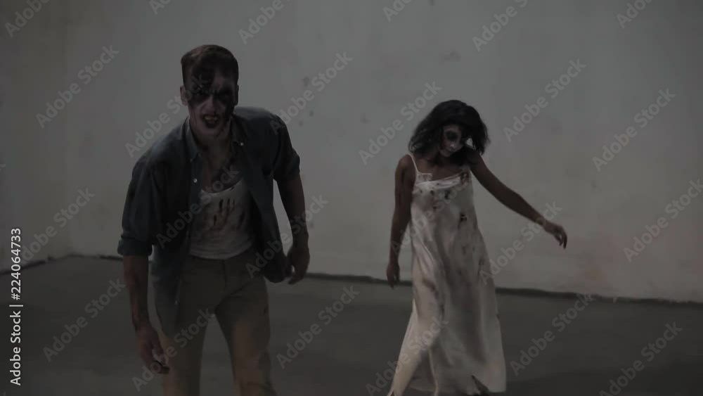 Creepy scene of a two male and female zombies coming on in empty ...