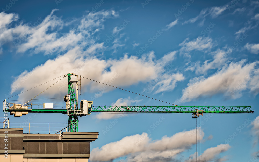 Green tower crane on a background of clouds Green tower crane on a background of clouds