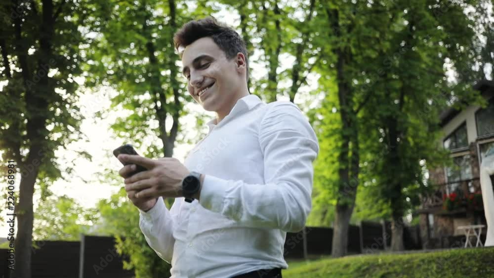 Smiling happy attractive young man use phone walk in park forest internet sunset face sun technology handsome lifestyle mobile street business smartphone boy tourist sms close up portrait Smiling happy attractive young man use phone walk in park forest internet sunset face sun technology handsome lifestyle mobile street business smartphone boy tourist sms close up portrait
