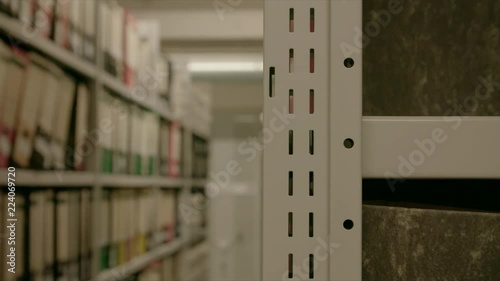 In an archive with many shelves, shelves shift in the background. The image can be used for the integration of archive texts in films and reports. Thanks to the 50 frames it can be slowed down.