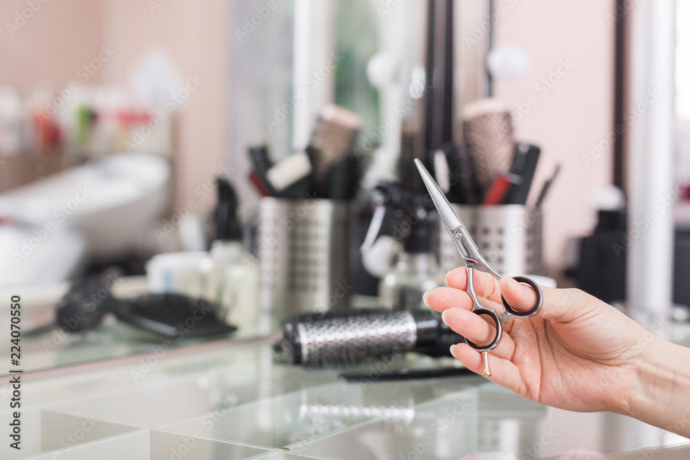 Hand of a hairdresser with scissors on the background of a hairdressing workstation. Hairdresser working desk. Preparation for cutting hair. Beauty salon working desk. Hand of a hairdresser with scissors on the background of a hairdressing workstation. Hairdresser working desk. Preparation for cutting hair. Beauty salon working desk.