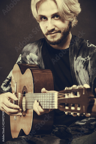 Blonde man playing acoustic guitar photo