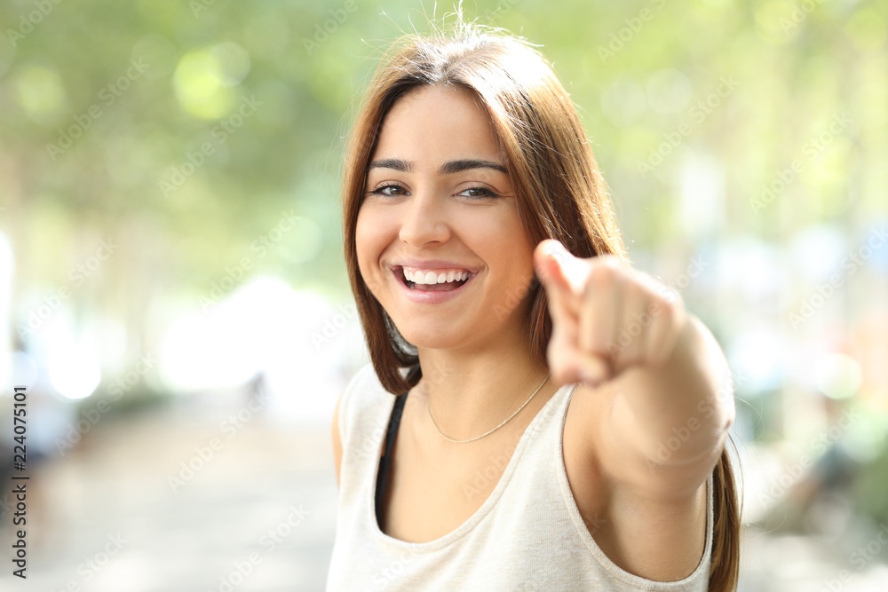 Pretty girl pointing at camera outdoors