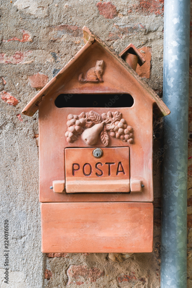 Old clay mailbox in Italian town. Orange mailbox. Close up.