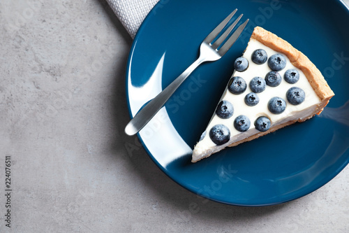 Piece of tasty blueberry cake and space for text on gray table, top view