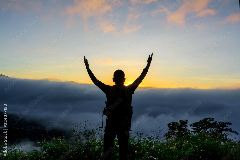 Silhouette of man standing with near a camping tent at sunrise ,success concept.