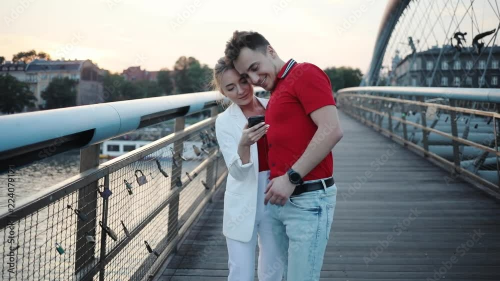 Smile couple using smartphone on bridge in city attractive beautiful handsome city lifestyle love man mobile phone boyfriend cell girlfriend together adult cellphone female portrait slow motion Smile couple using smartphone on bridge in city attractive beautiful handsome city lifestyle love man mobile phone boyfriend cell girlfriend together adult cellphone female portrait slow motion