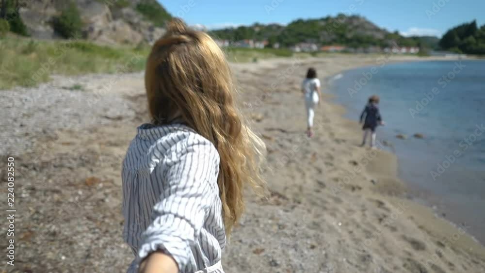 A great family adventure. Follow me. Young Woman with children Leading her husband walking towards rocky northern beach. Slow motion A great family adventure. Follow me. Young Woman with children Leading her husband walking towards rocky northern beach. Slow motion