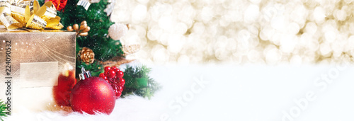 gift box and ball decoration under christmas tree on white fer with gold bokeh light background with snow fall.banner mock up for display of design or content.