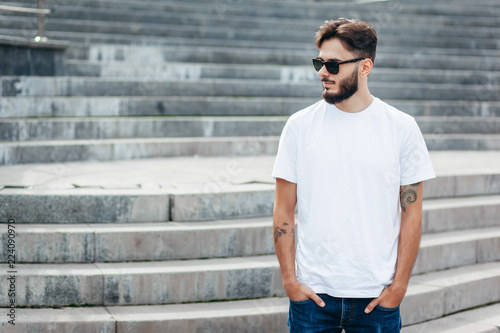 A young stylish man with a beard in a white T-shirt and glasses. Street photo © andrew_shots