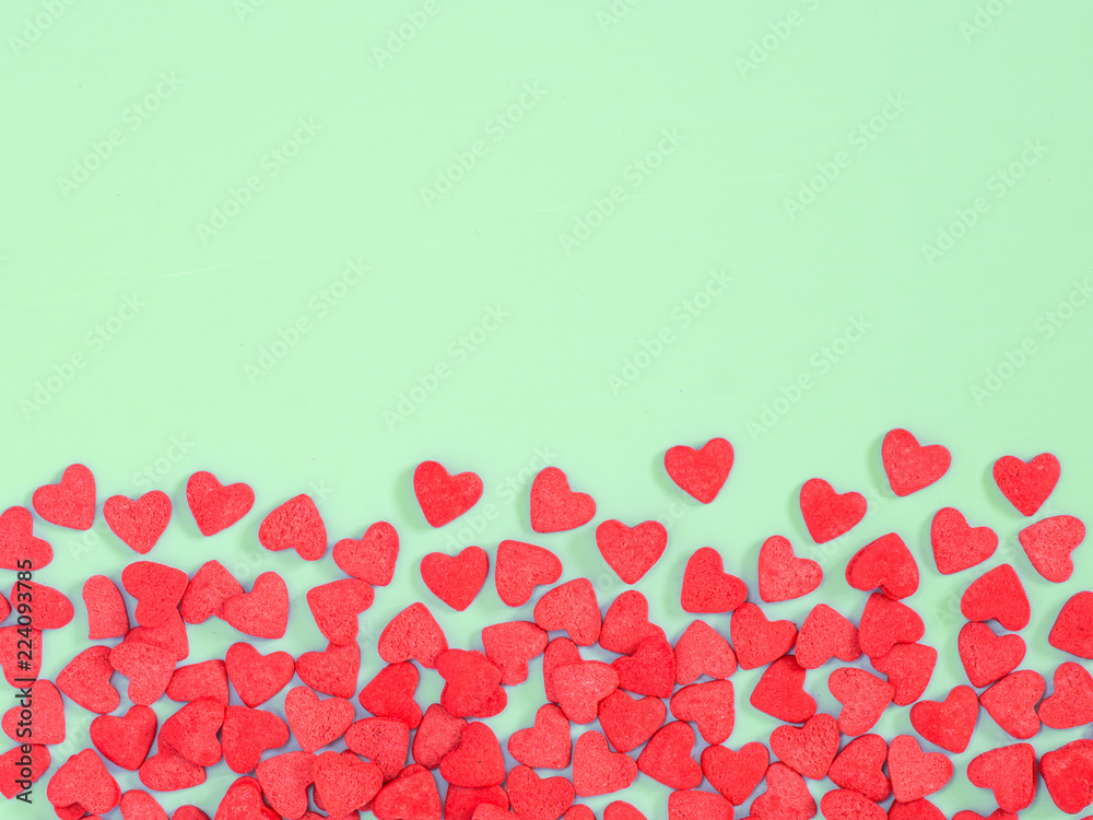 Border frame of red hearth-shape sprinkles on green background with copyspace. Top view or flat lay Border frame of red hearth-shape sprinkles on green background with copyspace. Top view or flat lay