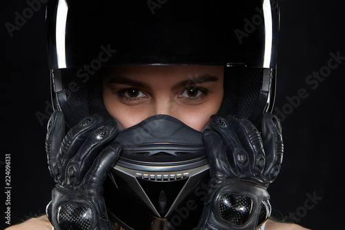 Canvas Print Beautiful young woman in black leather gloves and protective motorbike helmet in studio