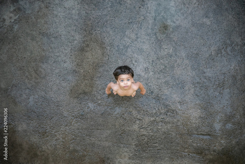 Cute baby boy toddler - naked on a wet gray floor - Top view