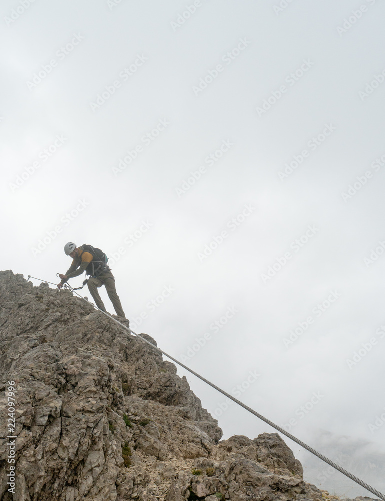 young attractive male mountain climber on a steep and exposed Via Ferrata in Alta Badia in the South Tyrol in the Italian Dolomites