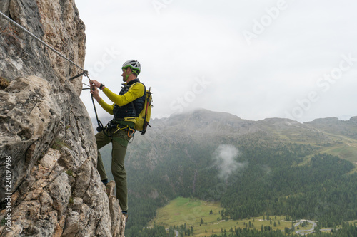 young attractive male mountain climber on a steep and exposed Via Ferrata in Alta Badia in the South Tyrol in the Italian Dolomites