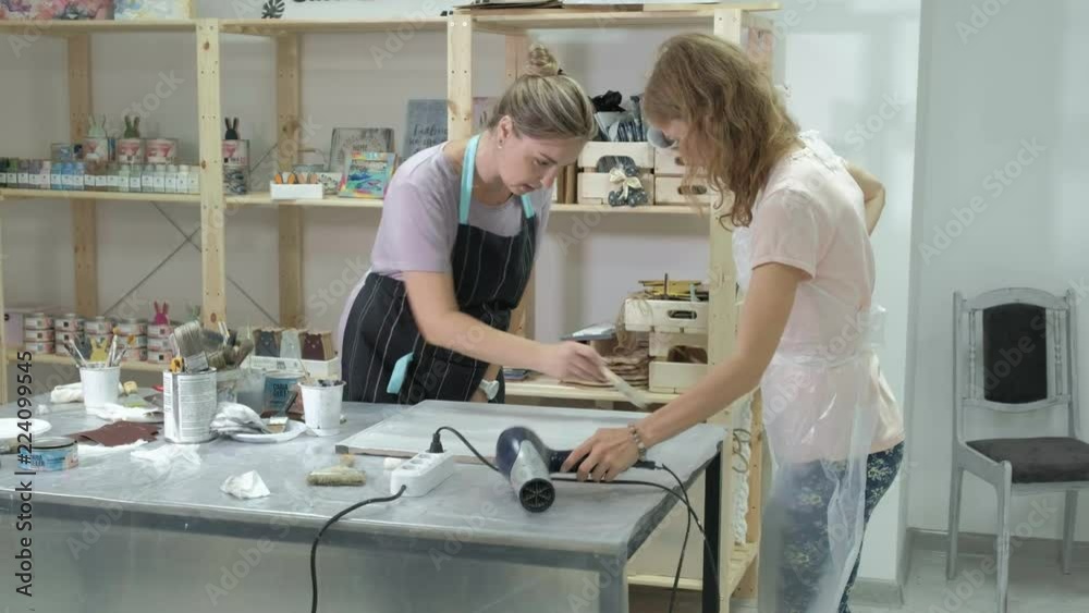 The woman in the workshop is working on wooden boards, creating an effect of antiquity The woman in the workshop is working on wooden boards, creating an effect of antiquity