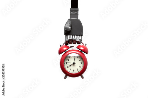 Toy robot hand is holding a red alkarm clock isolated on white background. Digital reminder.