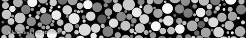 Abstract horizontal banner of circles of different sizes in shades of gray colors on black background