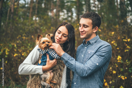 Pretty couple with little yorkshire terrier walking in the forest. © bedya