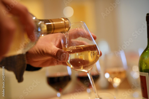 Man serving glass of white wine in winery