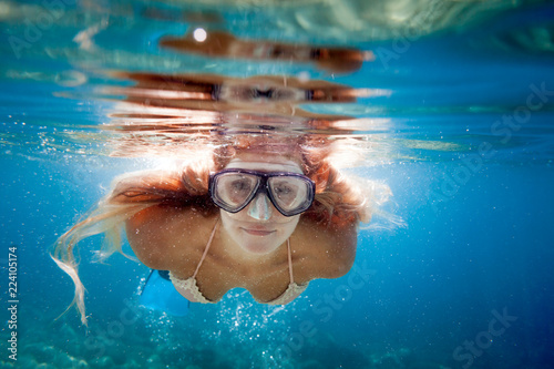 Beautiful woman with long hair underwater snorkeling in the tropical water