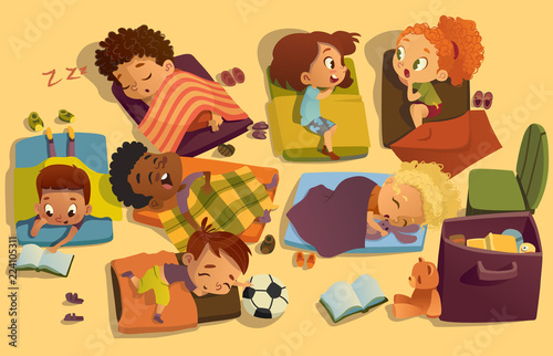 Nap time in the kindergarten. Group of multiracial girls and boys have a nip time at a colorfill nap mats. Preschool dream time. Two girls gossip during daytime sleep