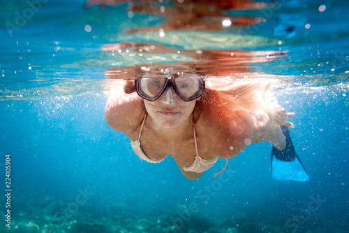 Smiling woman snorkeling in clear water, underwater tropical sea