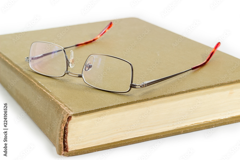 Classic men's eyeglasses on closed old book close-up Classic men's eyeglasses on closed old book close-up