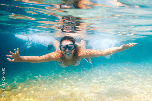 Smiling woman with mask underwater snorkeling in the clear tropical water