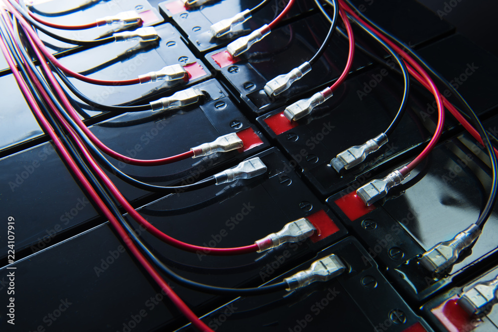 Battery powered. Industrial battery hooked up in parallel with long red ...