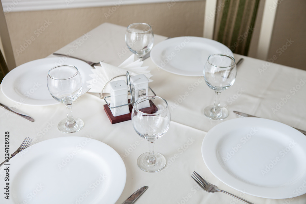 Glasses and glasses for wine on a table with a white tablecloth in a restaurant