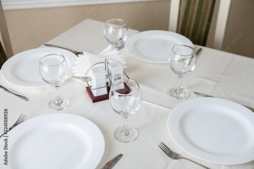 Glasses and glasses for wine on a table with a white tablecloth in a restaurant Glasses and glasses for wine on a table with a white tablecloth in a restaurant