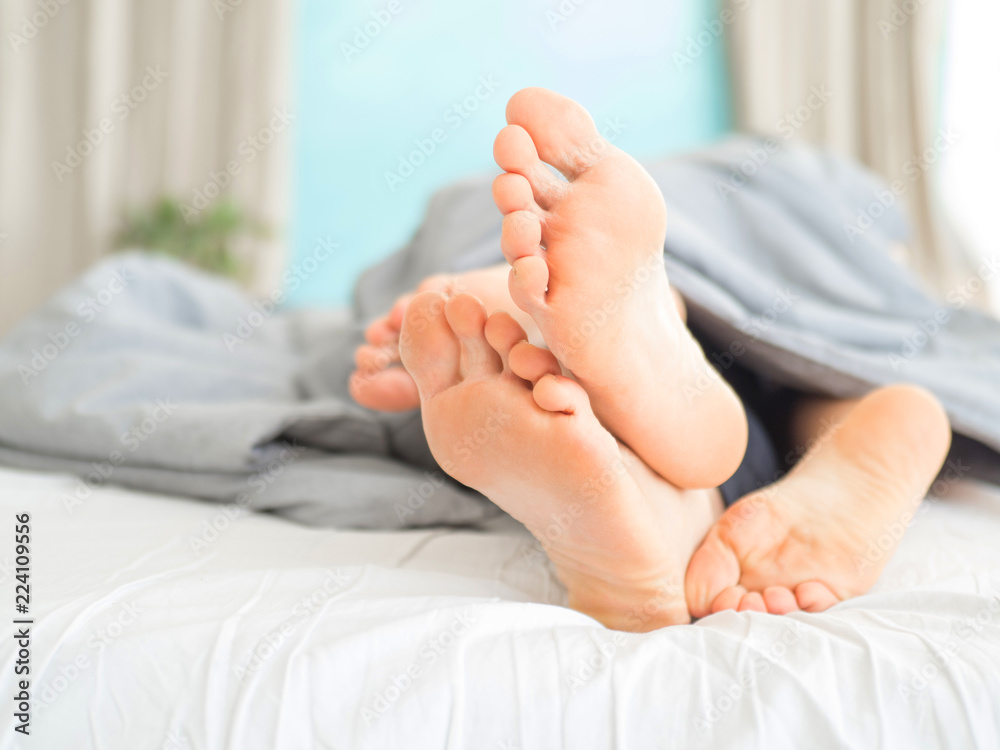 The legs from under the blanket. Young happy couple in bed at home. The legs from under the blanket. Young happy couple in bed at home.