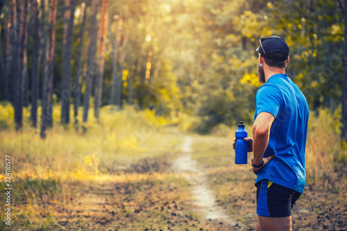A bearded athlete prepares for a morning run along a picturesque forest path. healthy lifestyle concept