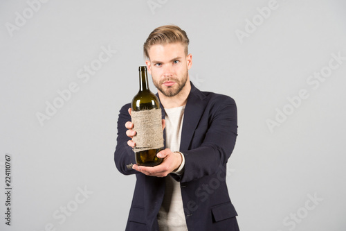 Would you like to try this. Sommelier offer bottle of wine. Professional wine degustation concept. Man formal suit with wine bottle in hand. Sommelier handsome confident guy on grey background