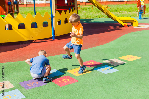Billede på lærred Two boys playing hopscotch in the summer outdoors