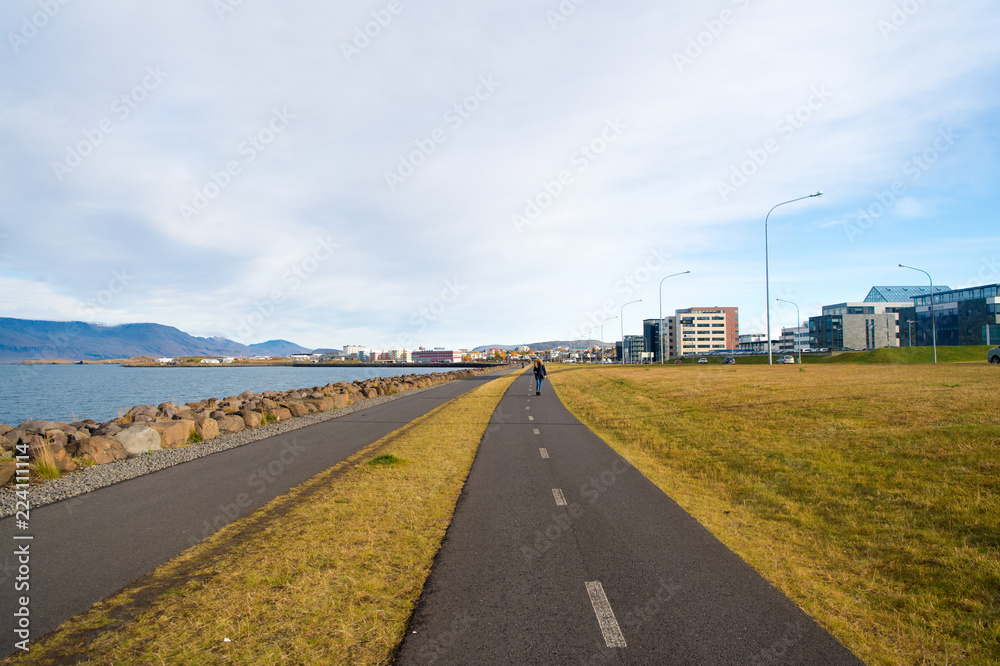 Reykjavik, Iceland - October 12, 2017: travel road along sea coast. Country road on cloudy sky. Miles of travel. Promenade road. The road will rise to meet the one who walks it