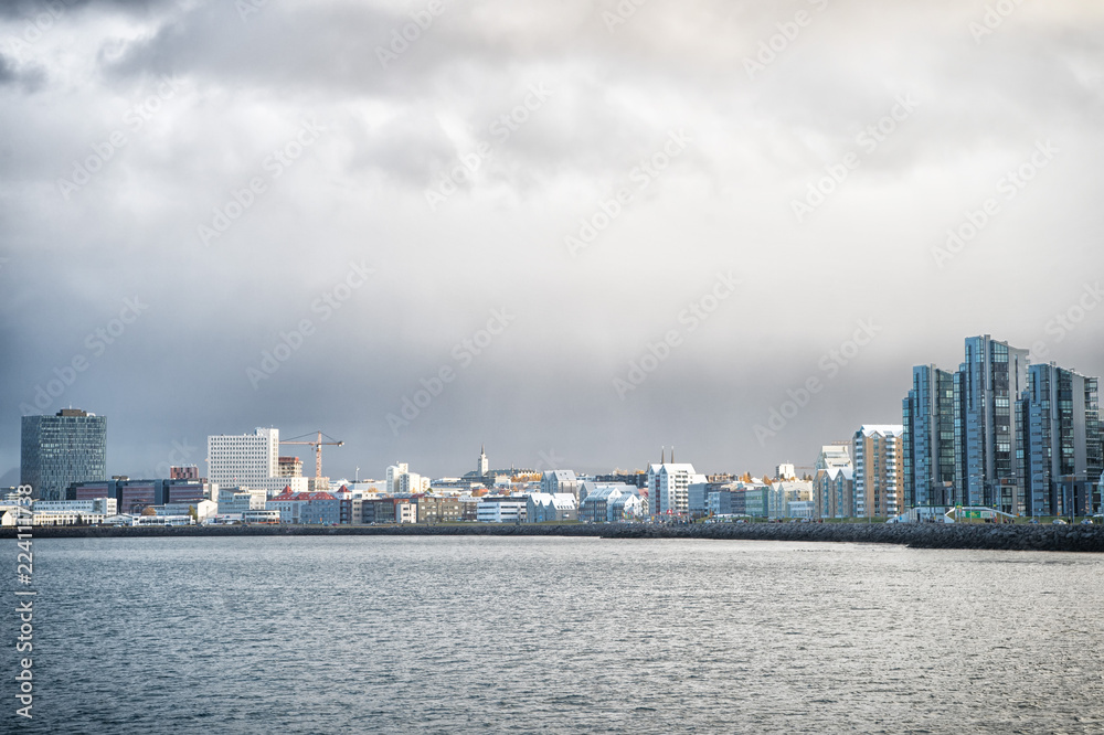 Reykjavik seascape dramatic cloudy sky. City on sea coast Iceland. Scandinavian seascape concept. Calm water surface and city with high buildings modern architecture. Scandinavian city at seashore Reykjavik seascape dramatic cloudy sky. City on sea coast Iceland. Scandinavian seascape concept. Calm water surface and city with high buildings modern architecture. Scandinavian city at seashore