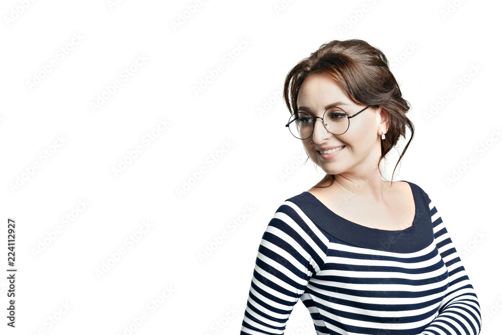A young beautiful woman in a striped tight blouse and in round glasses widely smiles white teeth. Looks to the left. Isolated on white background. A young beautiful woman in a striped tight blouse and in round glasses widely smiles white teeth. Looks to the left. Isolated on white background.