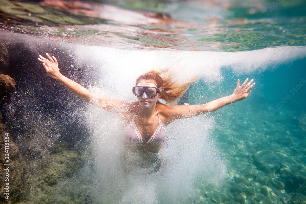 Young woman jumping to water, underwater image Young woman jumping to water, underwater image