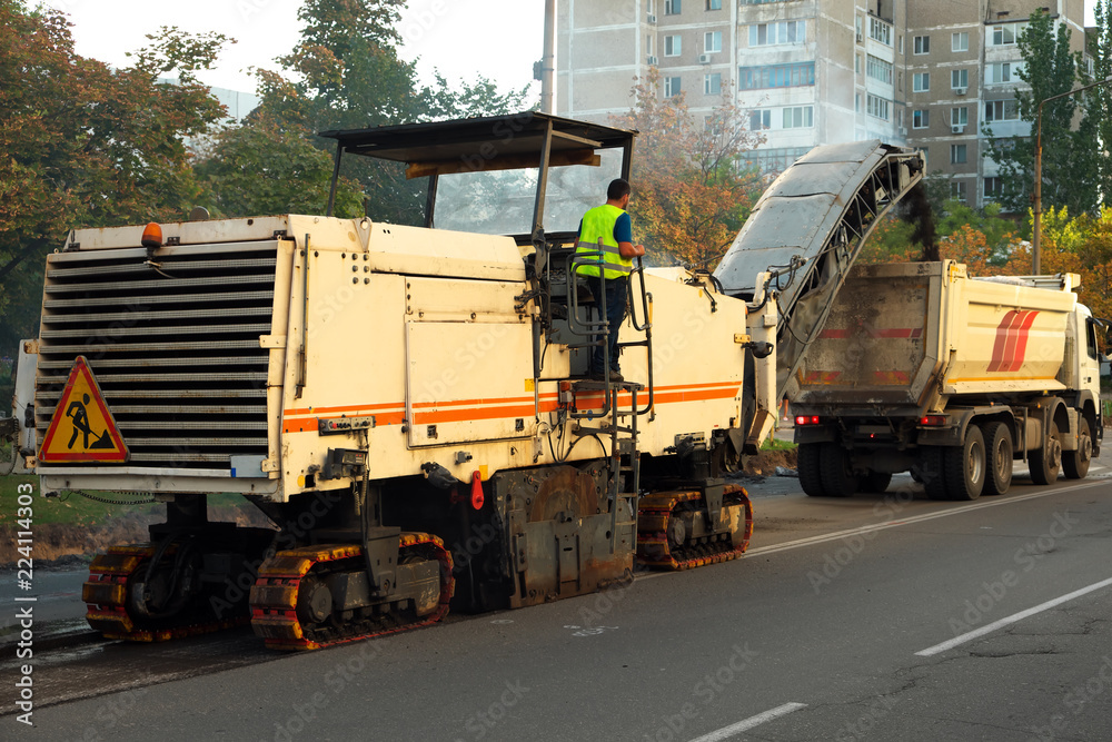 Road Scraping Machine Removes Old Asphalt During Construction. Roadworks repaving process