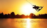 Wake Board a man does a trick at sunset on the Board on the water splashes
