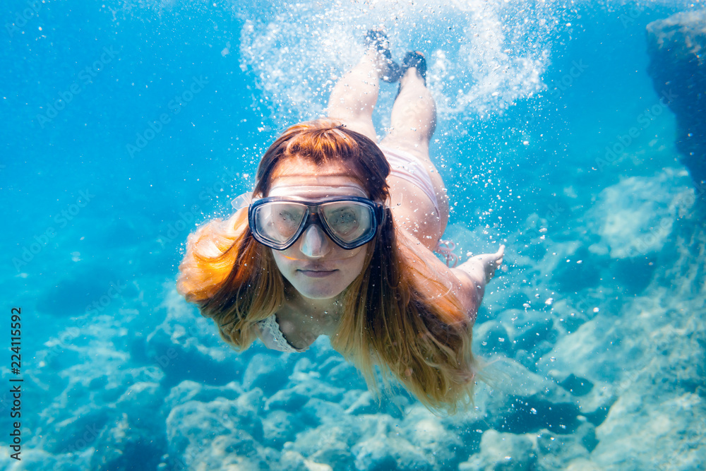 Fototapeta premium Young woman snorkeling underwater in the clear tropical water