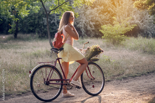 Beautiful attractive girl is walking in the park on a bicycle.