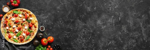 Obraz  z motywem Italian pizza and pizza cooking ingredients on black concrete background. Tomatoes on vine, mozzarella, black olives, herbs and spices. Copy space for text. Banner composition