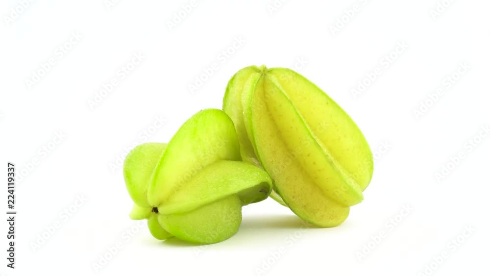 Two whole carambola fruits with water drops. Rotating on the turntable isolated on the white background. Close up. Macro.